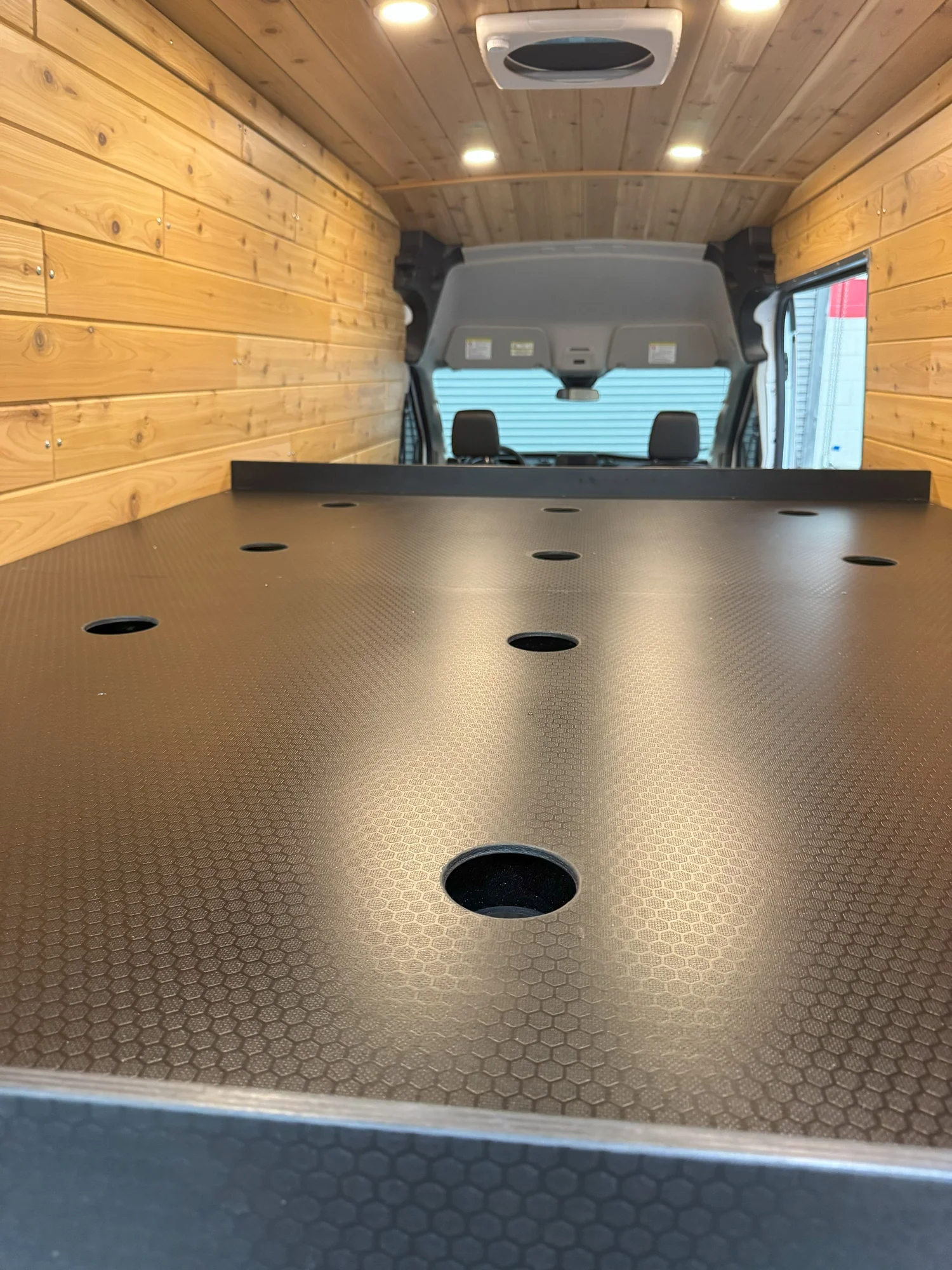 A black bed platform contrasts with the natural timber shell.