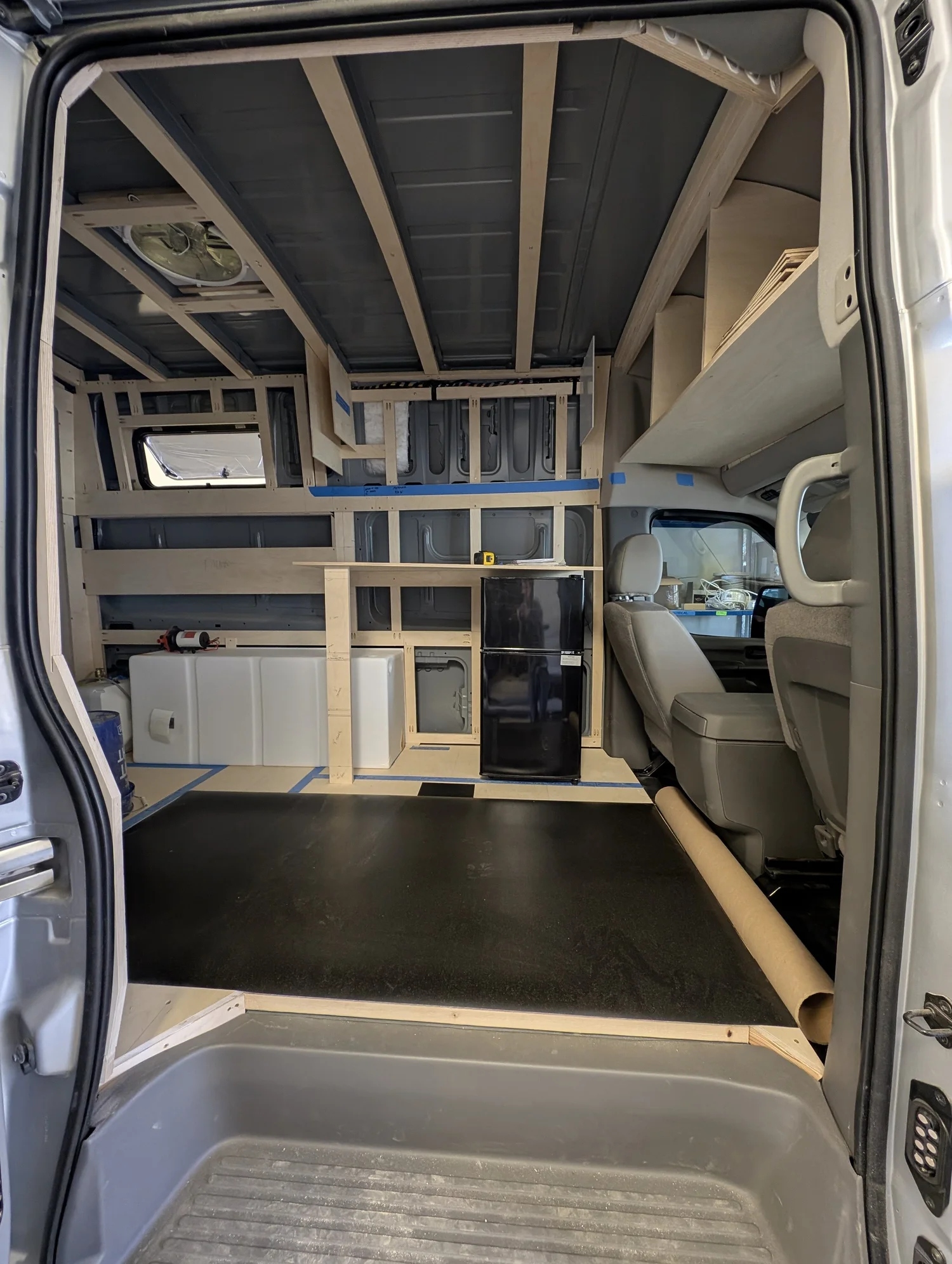 Completed Nissan NV3500 galley with sink, cabinetry, microwave, and tall refrigerator