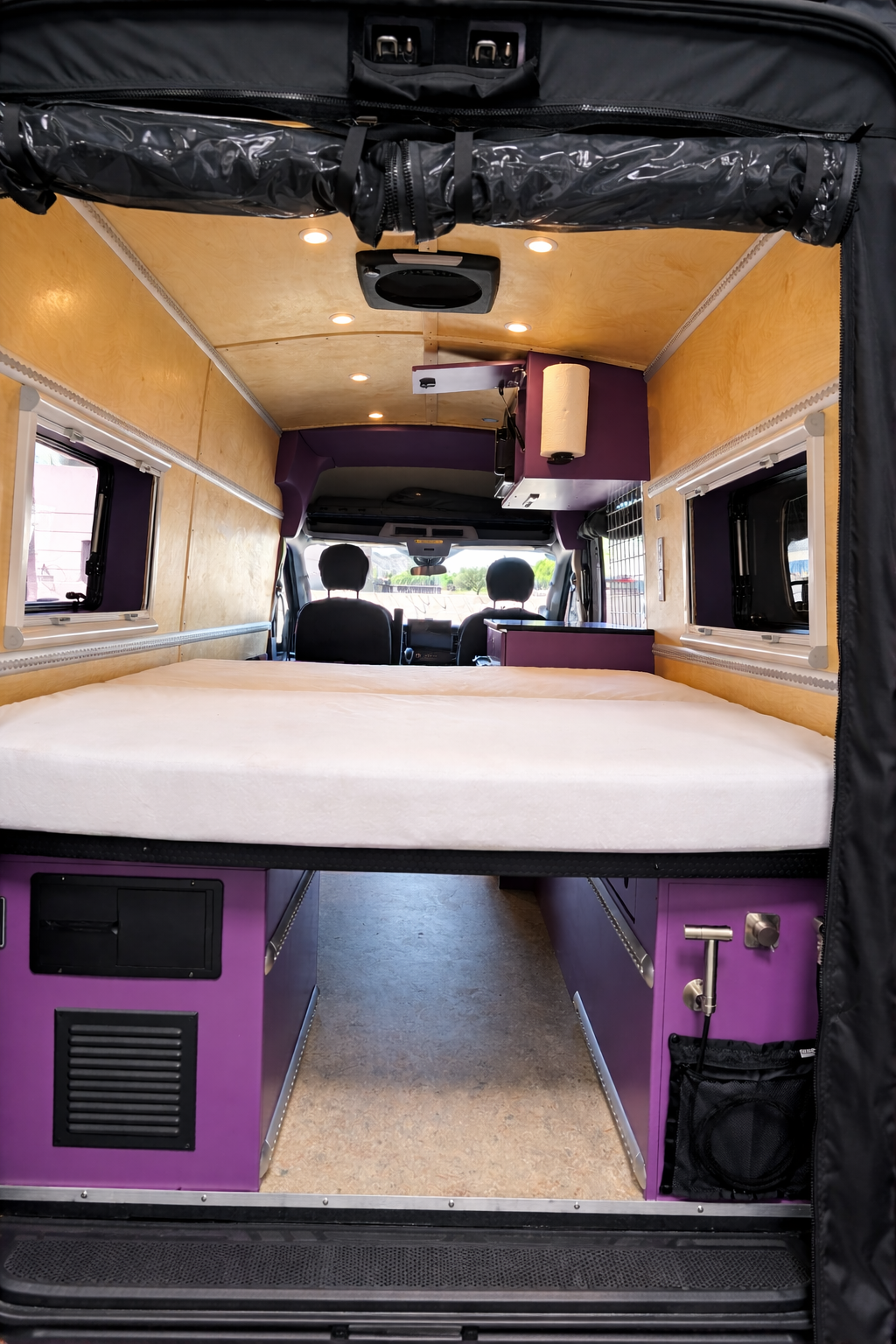 Finished rear view through Frida showing the bed, aisle and purple utility cabinets