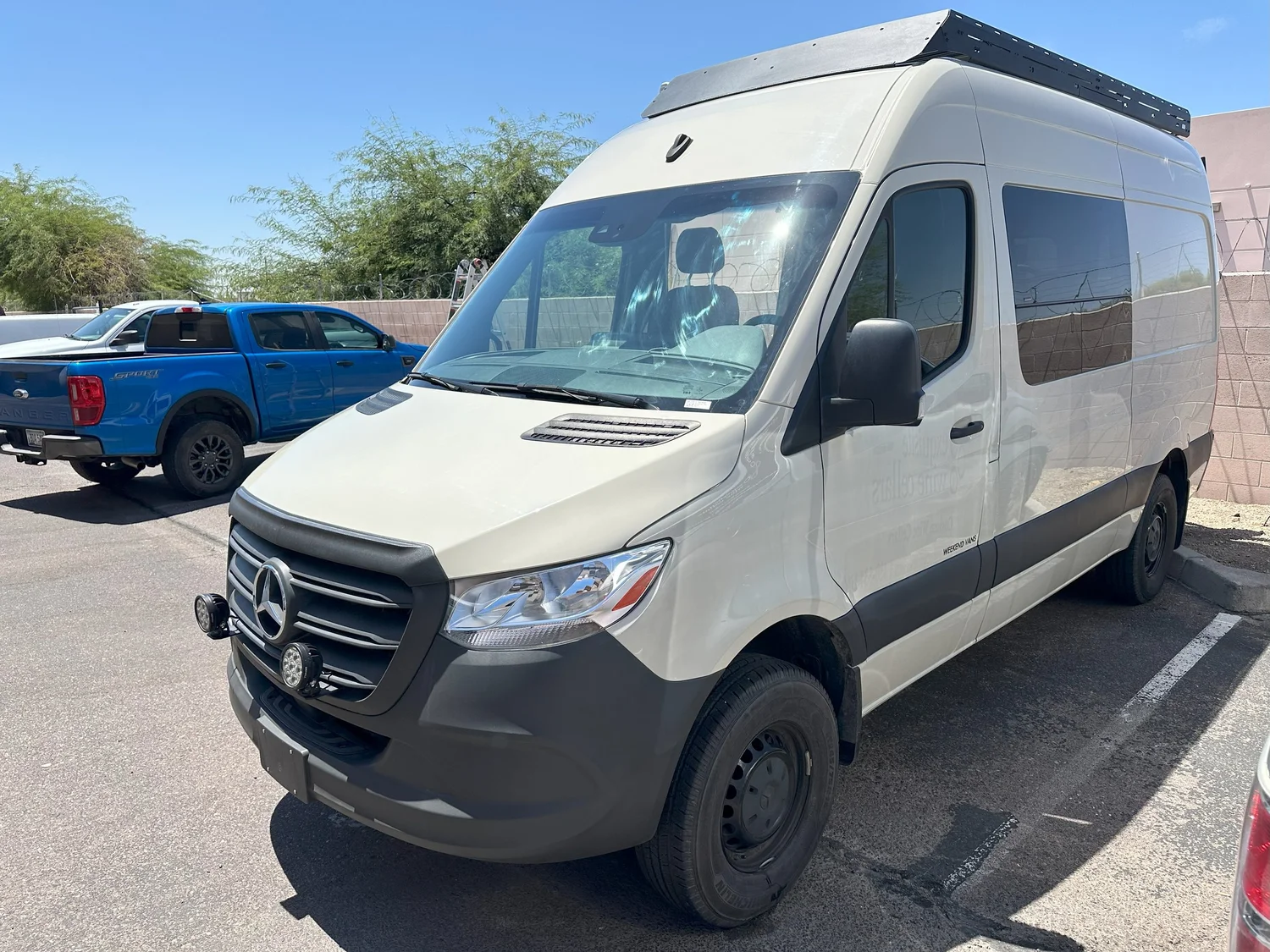 The completed Sprinter living area with bed, passenger seating, table, and warm slatted ceiling