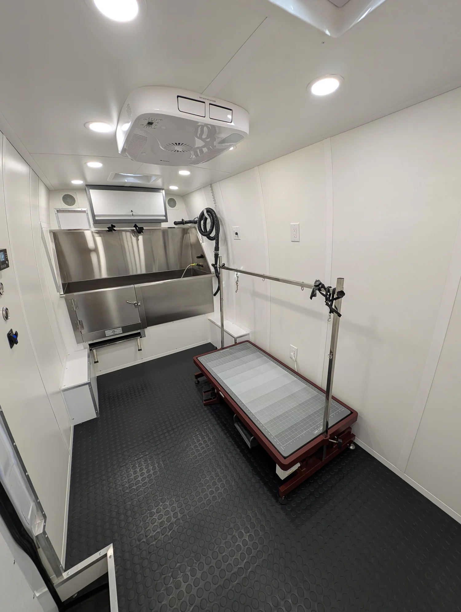 The rear equipment bay separates noise from the grooming table.