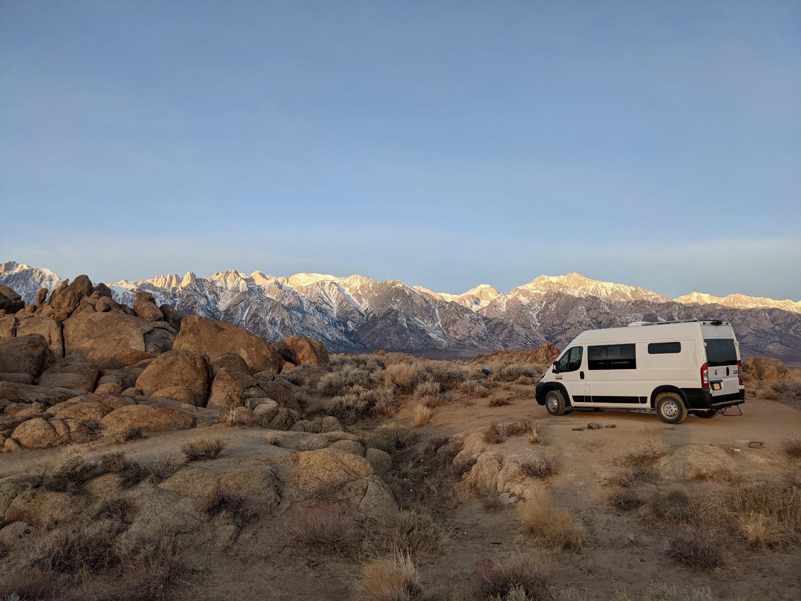 Custom camper van parked in the desert below snow-capped mountains