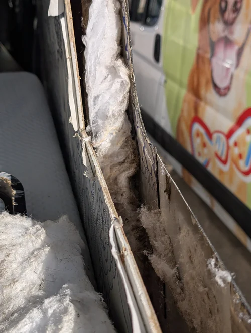 Interior wall opened to reveal moisture damage near a van window
